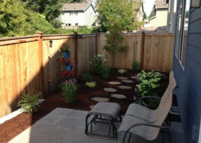 Fence and small landscaped area with mulch and stepping pavers.