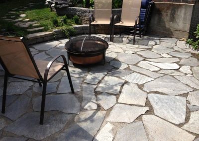 Firepit on flagstone patio with three chairs set up.