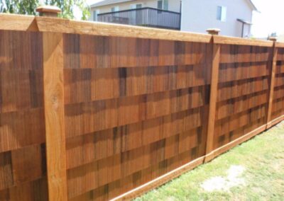Cedar fence with overlapping pieces next to residential lawn.