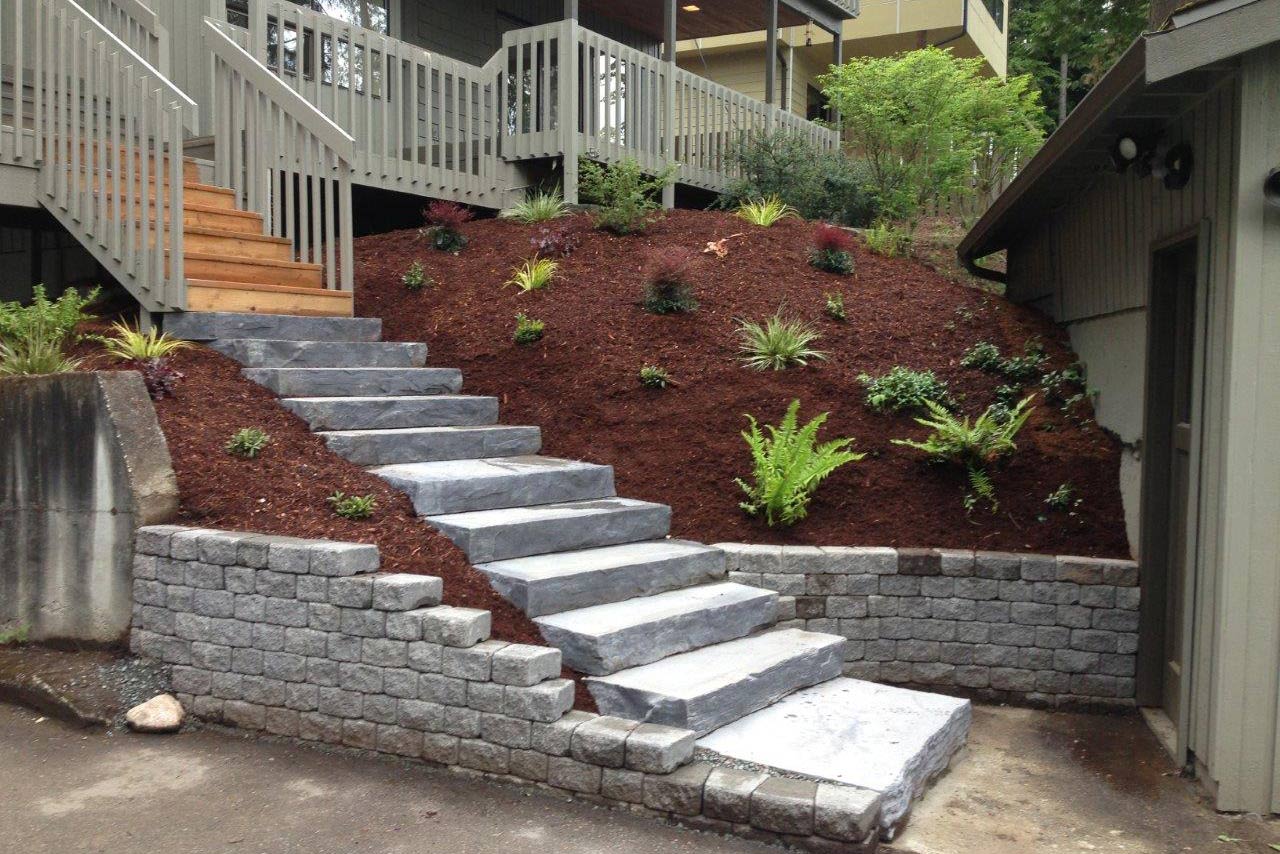 Image of a sloped landscape with rock steps and retaining walls protecting the yard from erosion, provided with our erosion control services.
